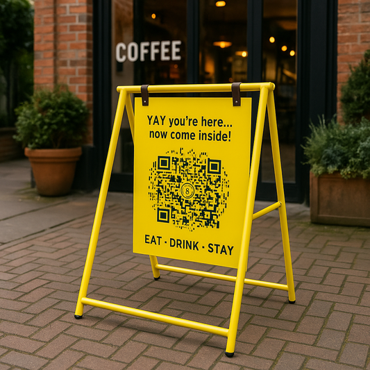 Yellow sign with QR code and text on a stand outside a coffee shop.