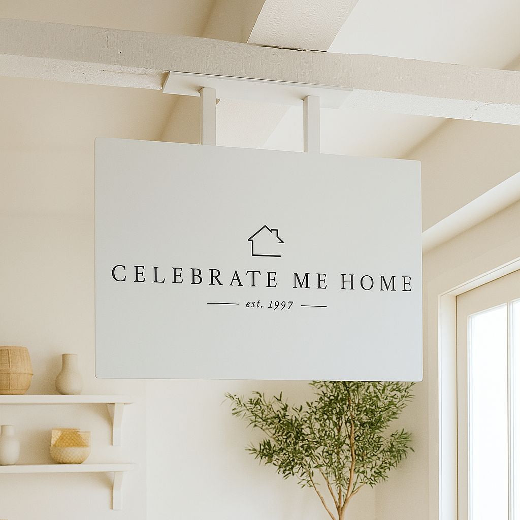 Nestled corner of a room with a 'Celebrate Me Home' sign, potted plants, and shelves.