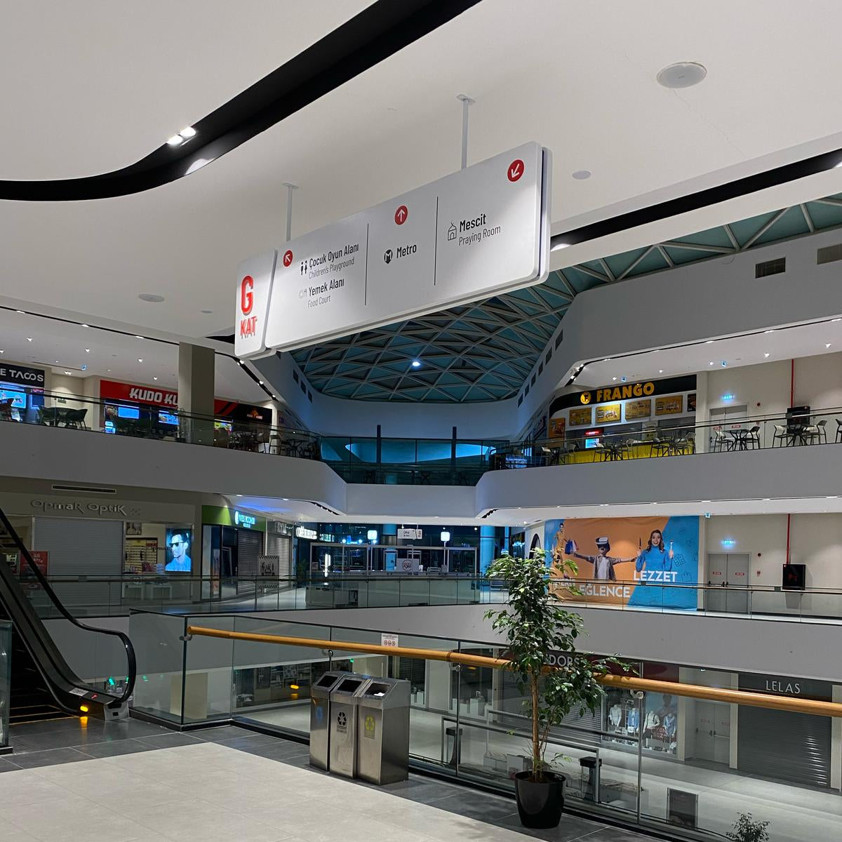 Interior of a modern shopping mall with escalators and signage.