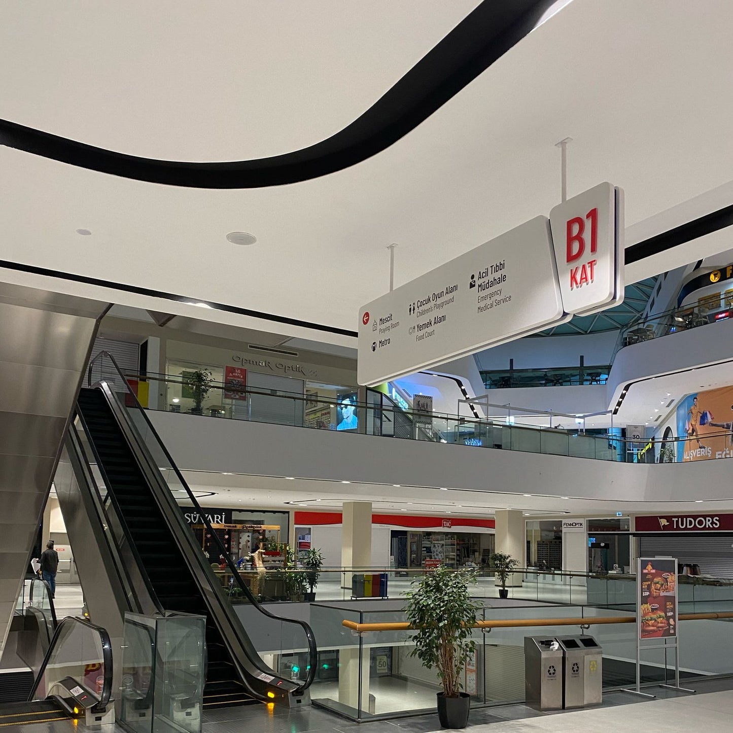 Modern shopping mall interior with escalator and directional signs.