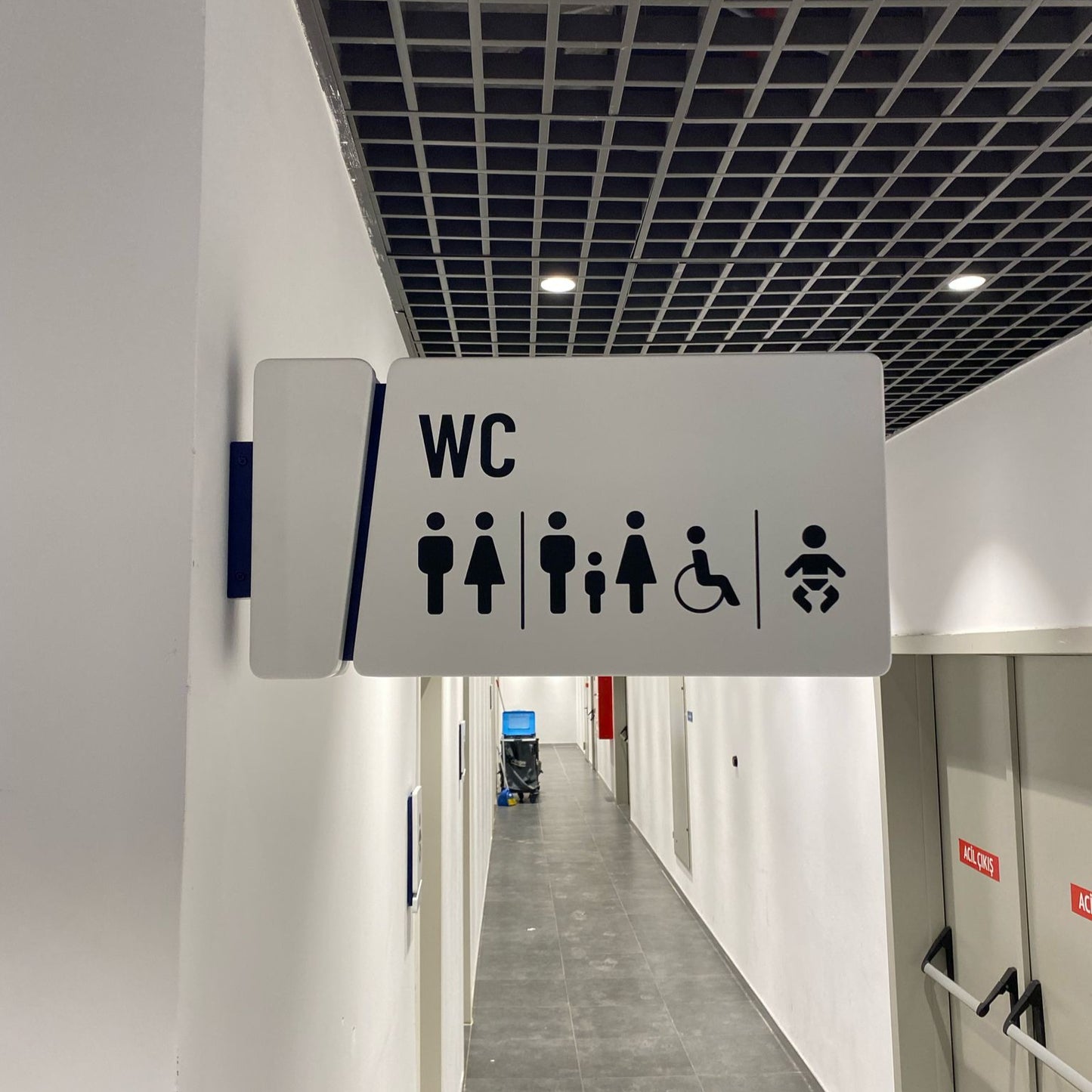Bathroom sign with accessibility icons in a hallway