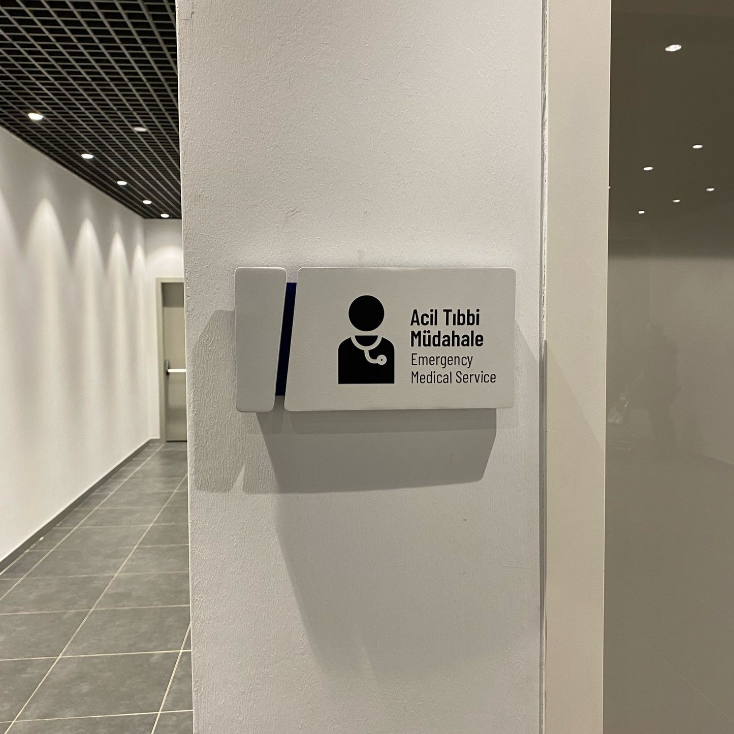 Emergency medical service station in a hallway with a white wall and tiled floor.