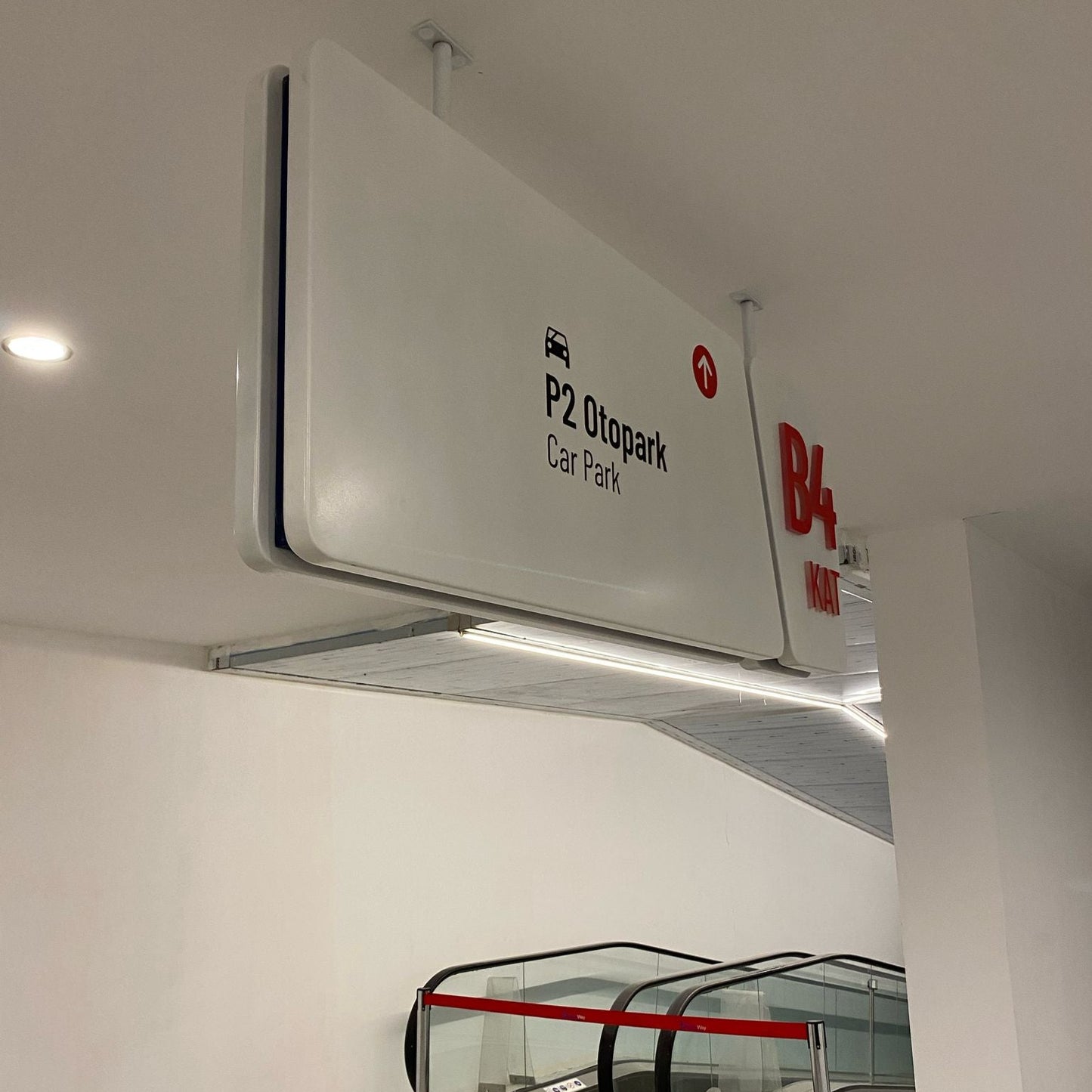 Signage for P2 Otpark Car Park and B4 Bus Stop on a wall above an escalator.