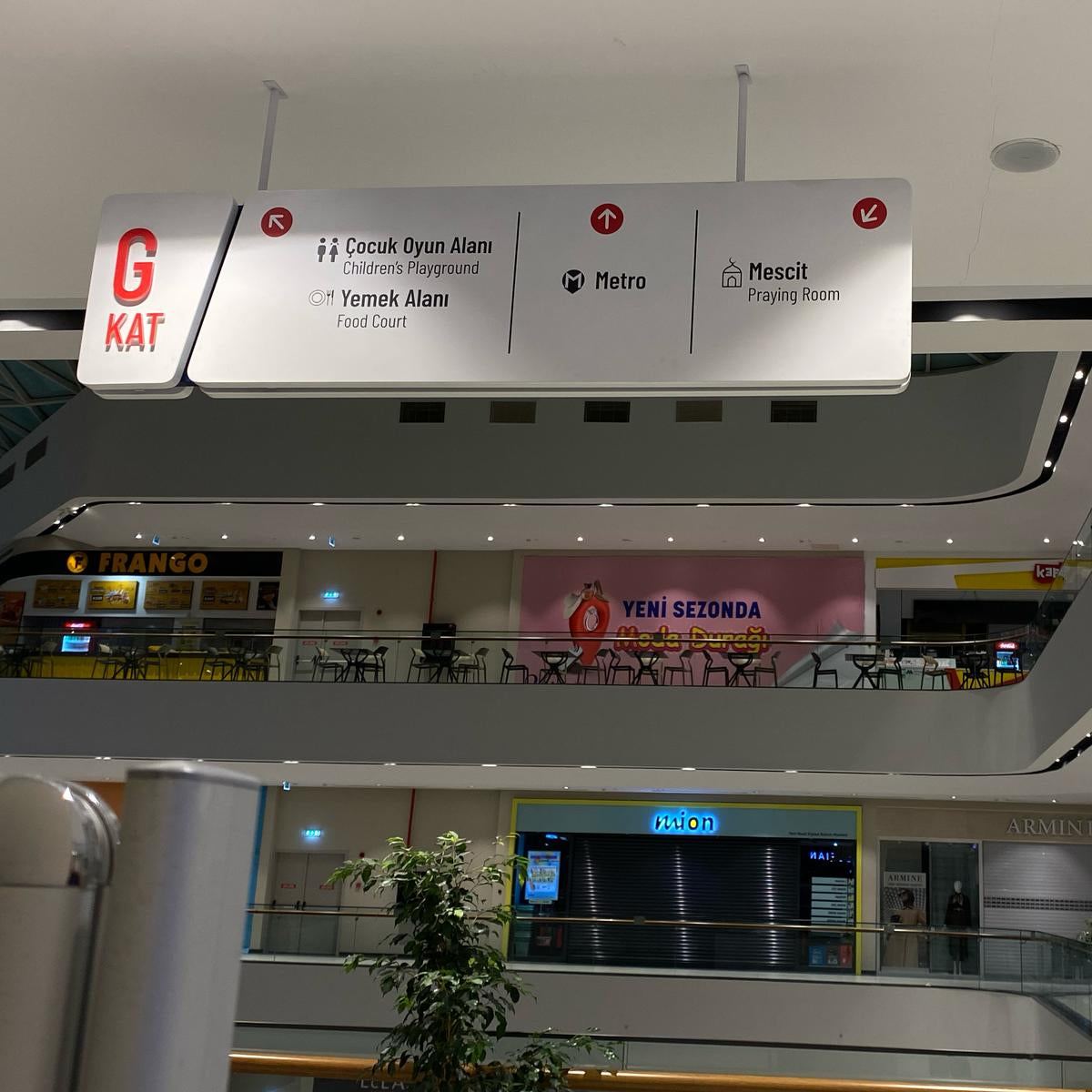 Interior of a shopping mall with a sign indicating floor levels and exits.