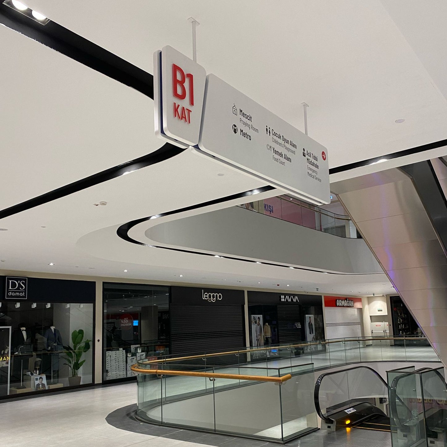 Modern shopping mall interior with escalators and signage