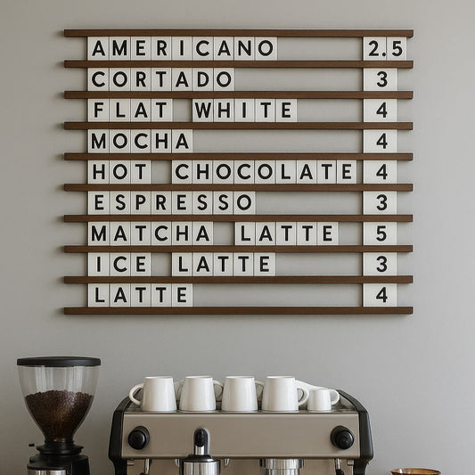 Coffee machine with a wall-mounted board displaying coffee drink names and quantities on a gray wall.