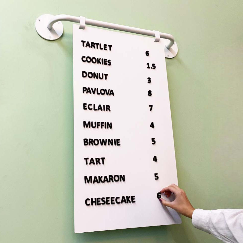 A wall-mounted magnetic menu board displaying a food menu with prices written in black on a purple background.