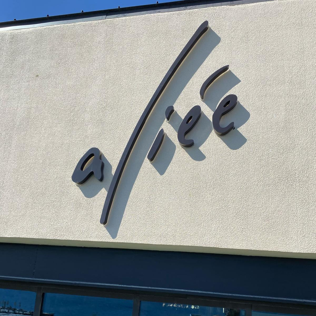 Logo on a building facade with water and dock visible in the reflection
