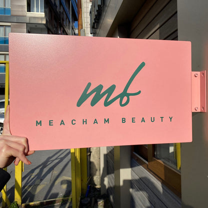Pink sign with 'mf Meacham Beauty' on a building exterior