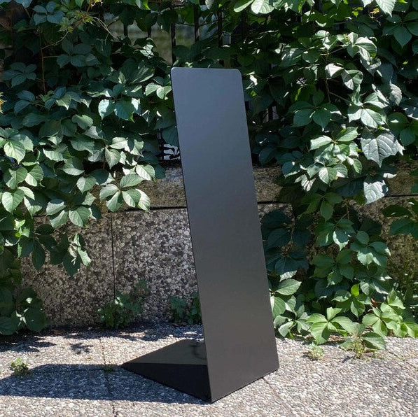 Tall, thin metallic object against a green leafy background