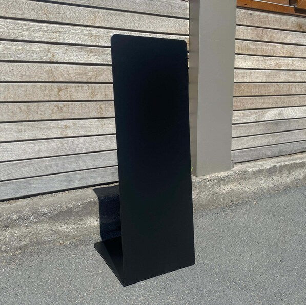 Black rectangular object leaning against a wooden wall.