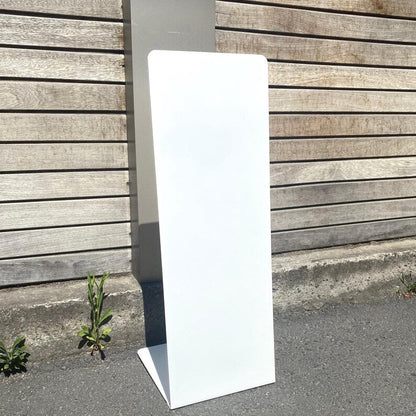 White pedestal stand against a wooden wall