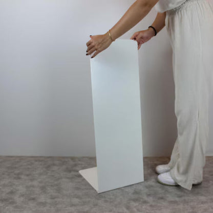 Person holding a white rectangular object against a plain background