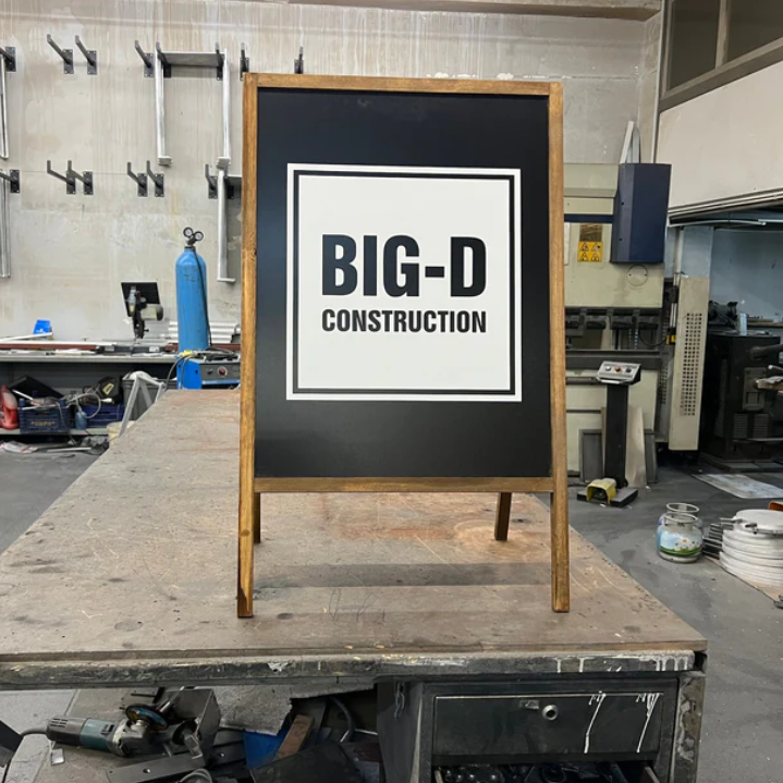Chalkboard sign with 'BIG-D Construction' on a workshop table