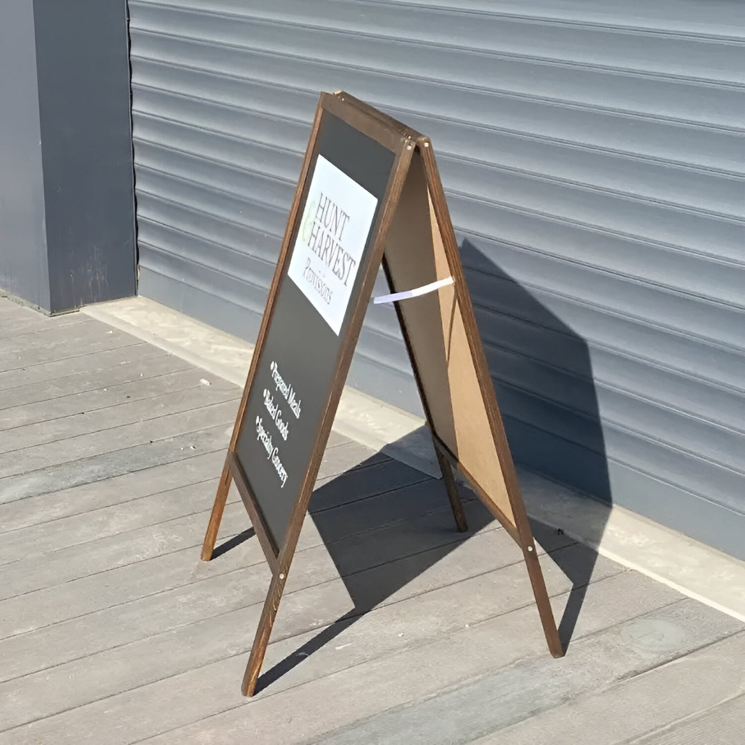 A-frame sign with a white poster on a wooden floor against a gray wall