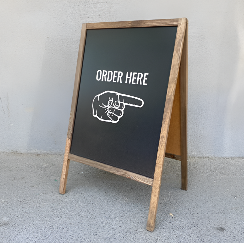 Chalkboard sign with 'ORDER HERE' and pointing hand illustration on a gray background