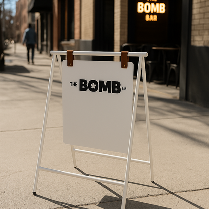 A-frame sign for 'The Bomb' in front of a building with a neon sign inside.