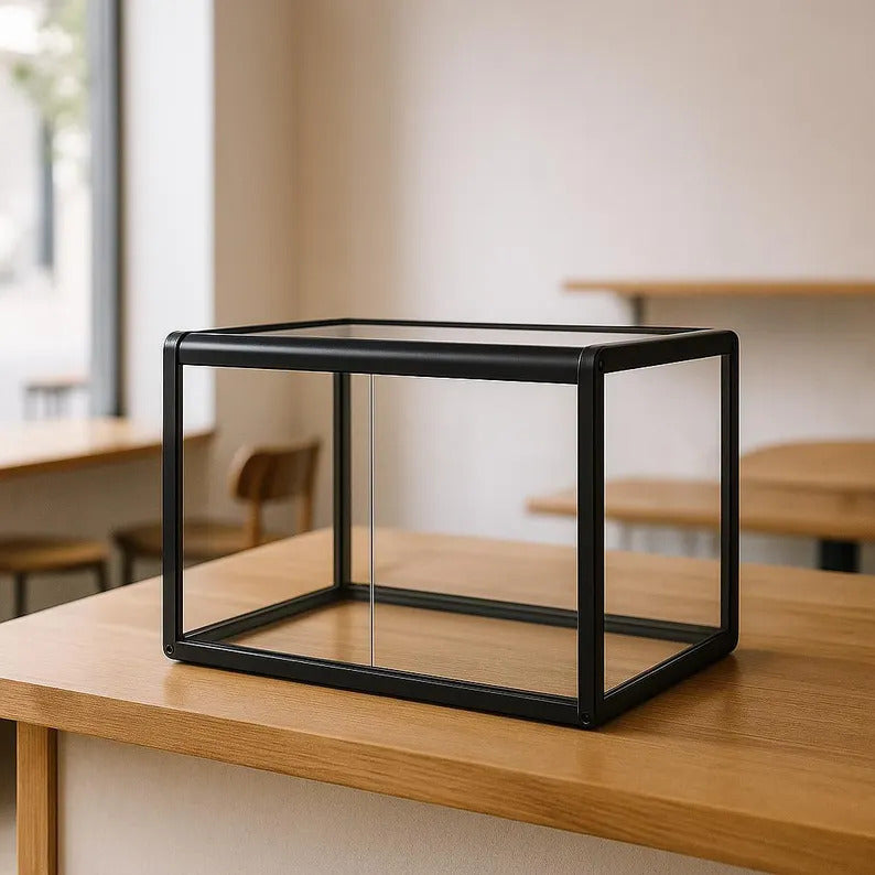 Black cube-shaped glass display case on a wooden table