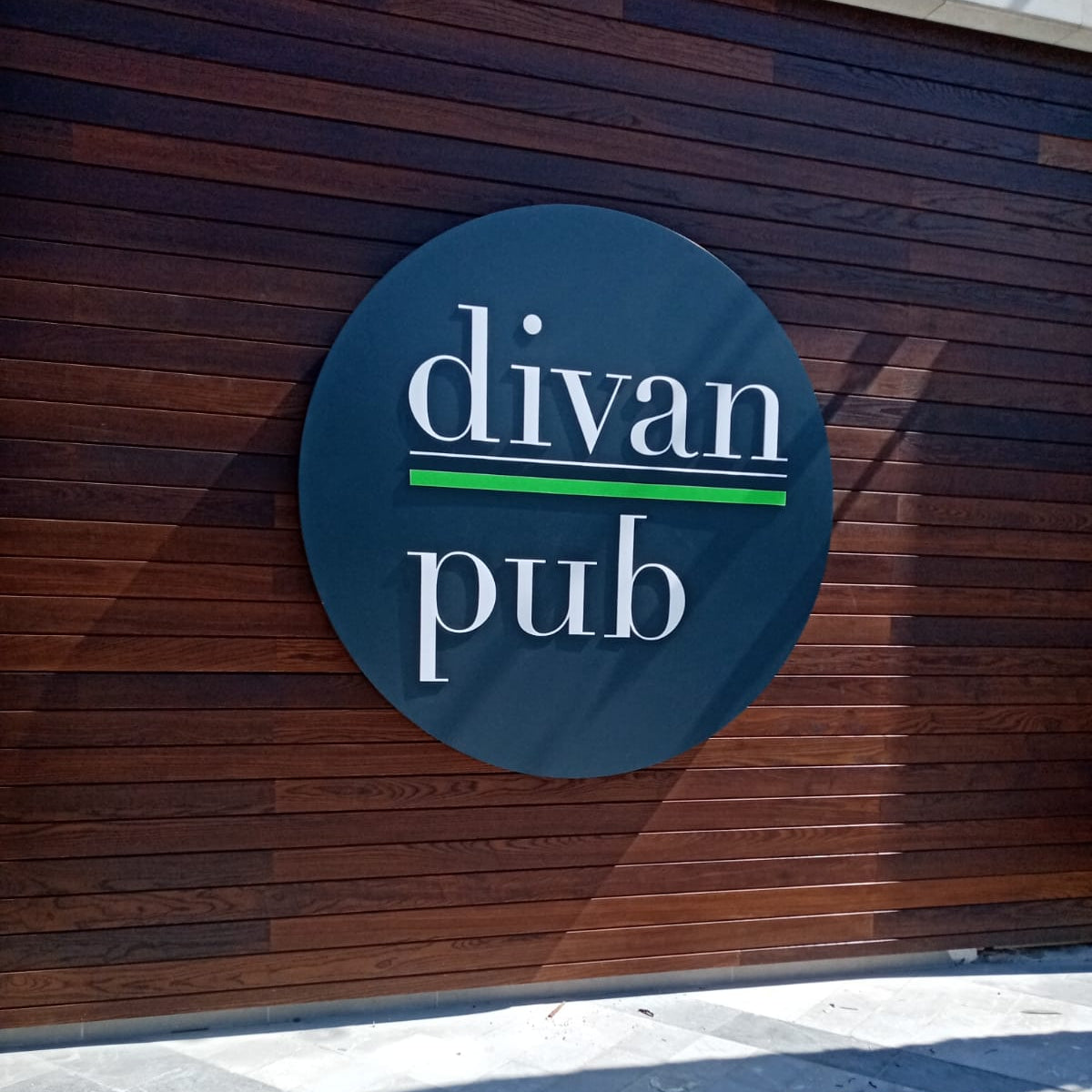 Round sign with 'divan pub' text on a wooden wall
