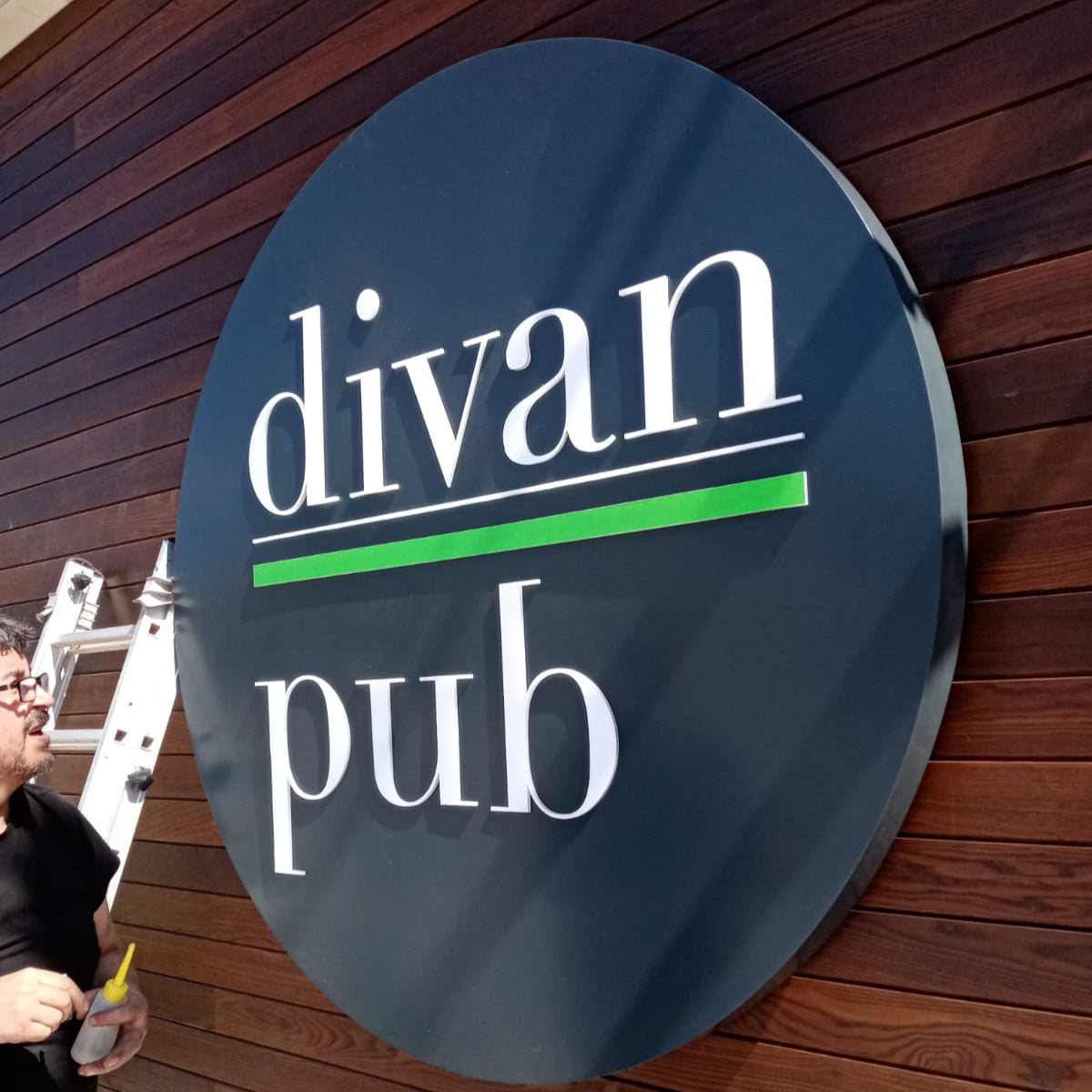 Round sign with 'divan pub' text on a wooden wall