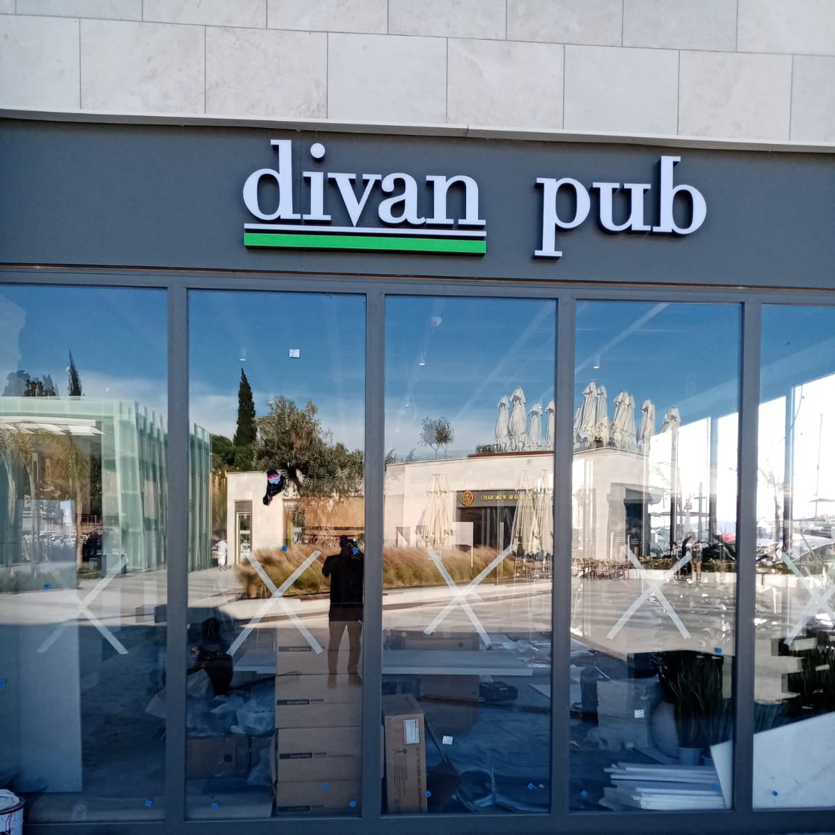 Divan Pub storefront with large glass windows and a visible reflection of the outside.