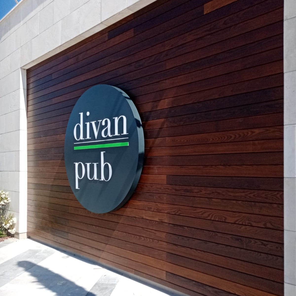 Round sign with 'divan pub' text on a wooden wall.