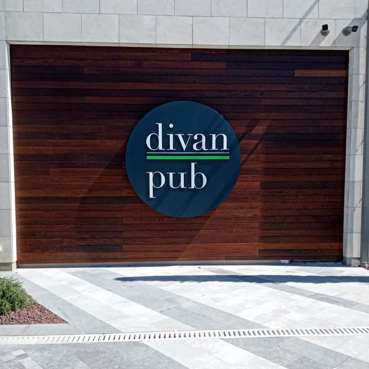 Wooden garage door with 'divan pub' logo on a building exterior.