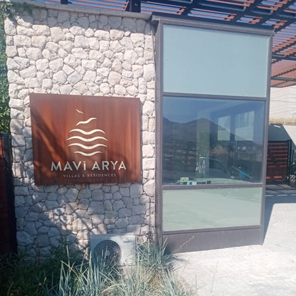 Mavi Arya logo on a stone wall next to a glass door