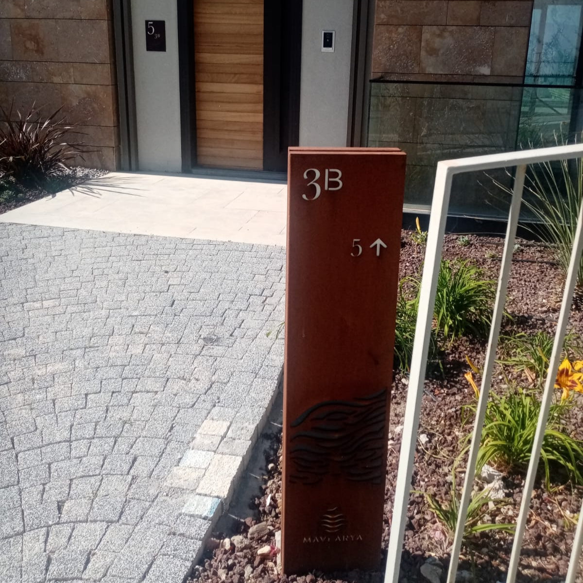 Modern house entrance with a wooden door and a metal address sign labeled '3B'.