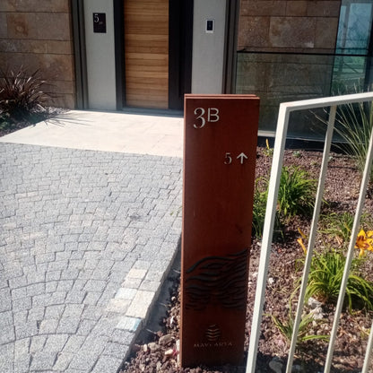 Modern house entrance with a wooden door and a metal address sign labeled '3B'.