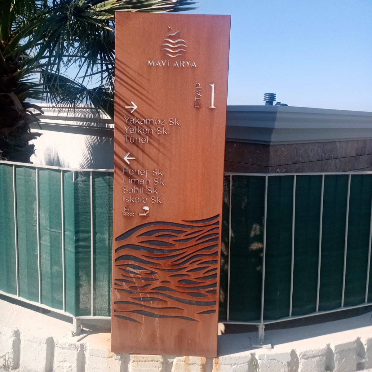 Brown directional sign with wave patterns in front of a building
