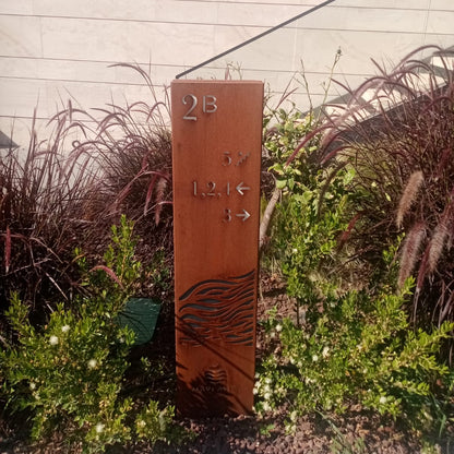 Metal sign with engraved text and symbols in a garden setting