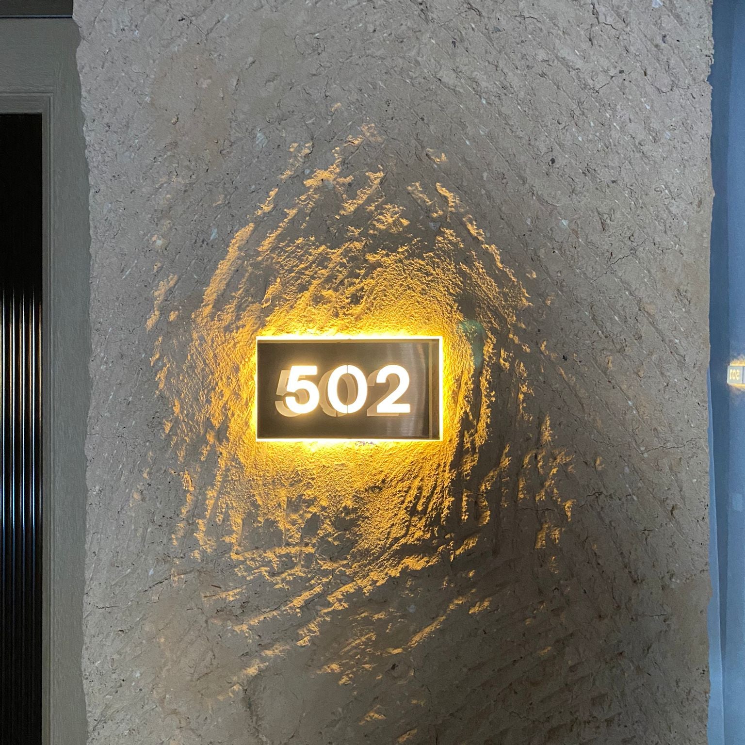  illuminated house number '502' on a textured stone wall