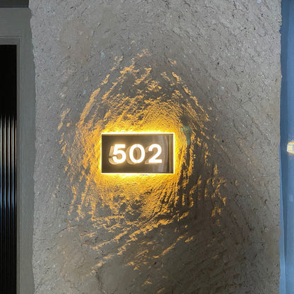  illuminated house number '502' on a textured stone wall