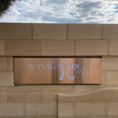 Brass sign with 'Avangarde' on a stone wall against a cloudy sky