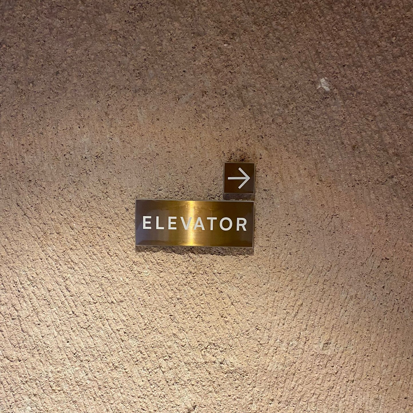 Elevator sign on a textured beige wall
