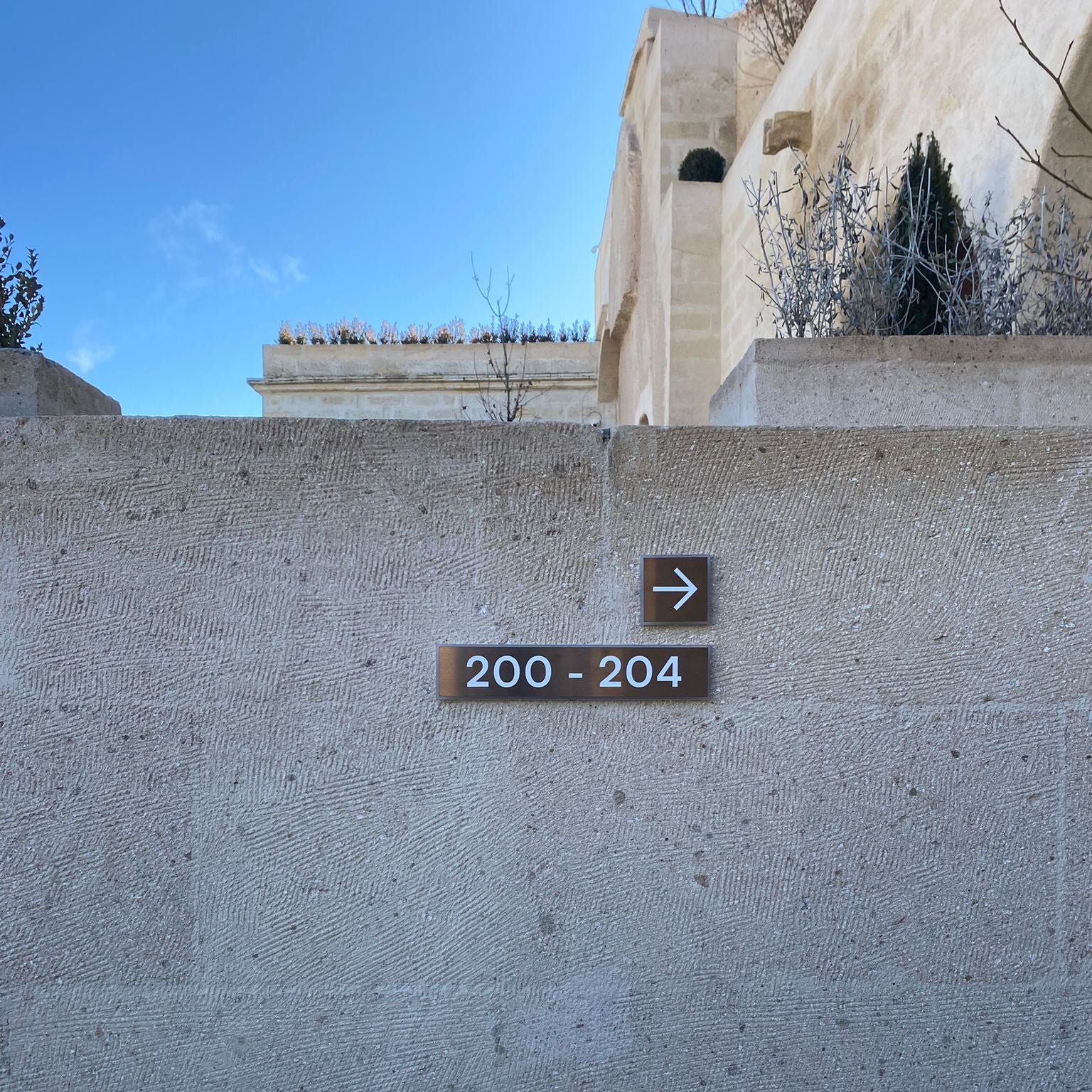 Address sign on a stone wall with a building in the background