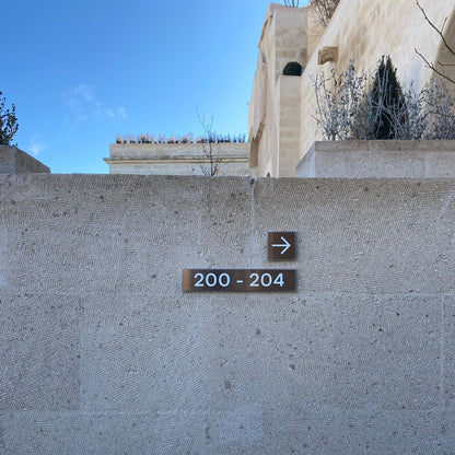 Address sign on a stone wall with a building in the background