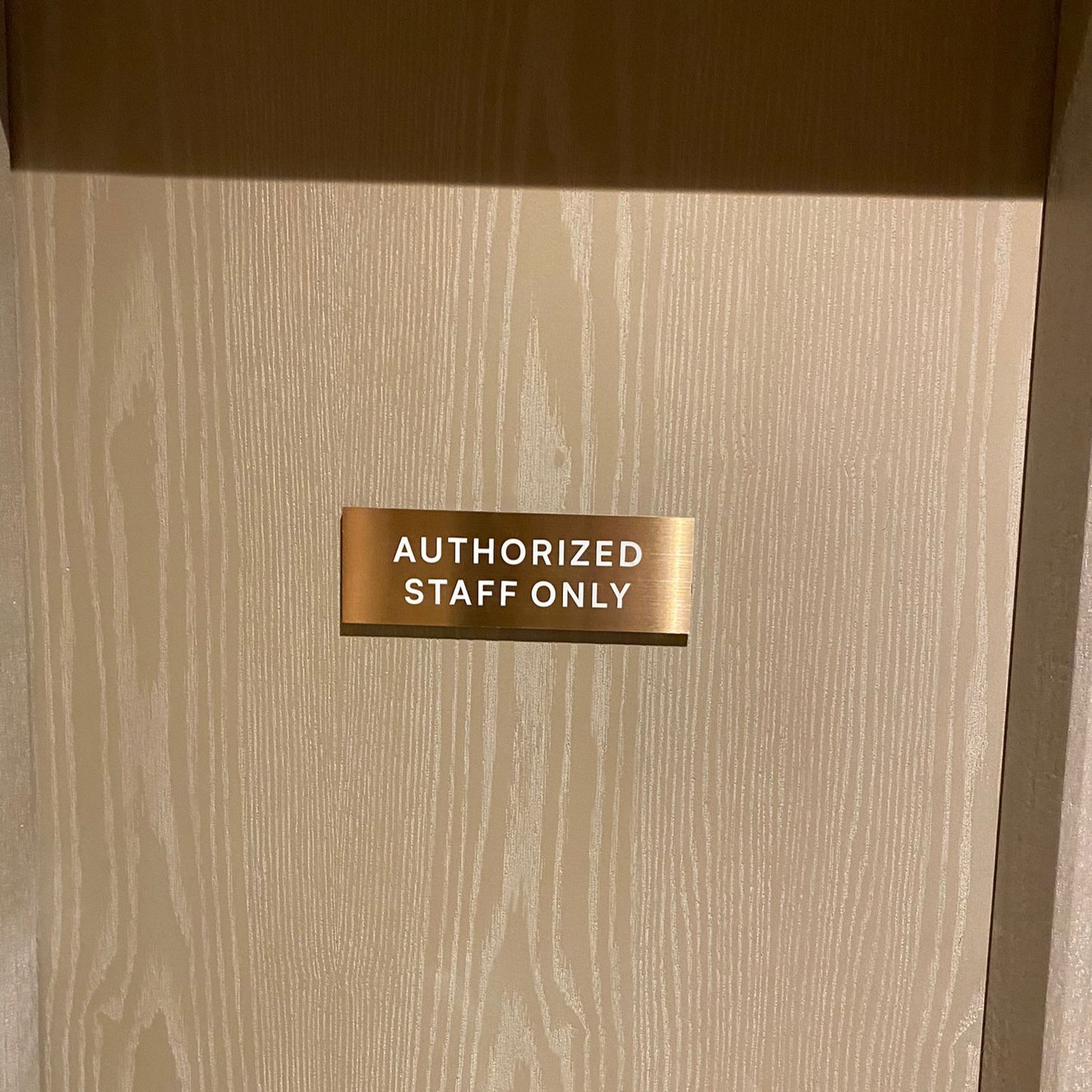 Beige door with a gold 'Authorized Staff Only' sign