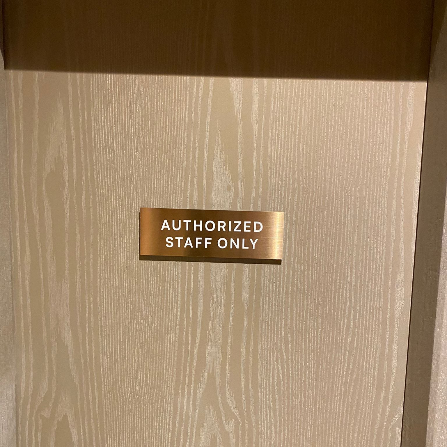 Beige door with a gold 'Authorized Staff Only' sign