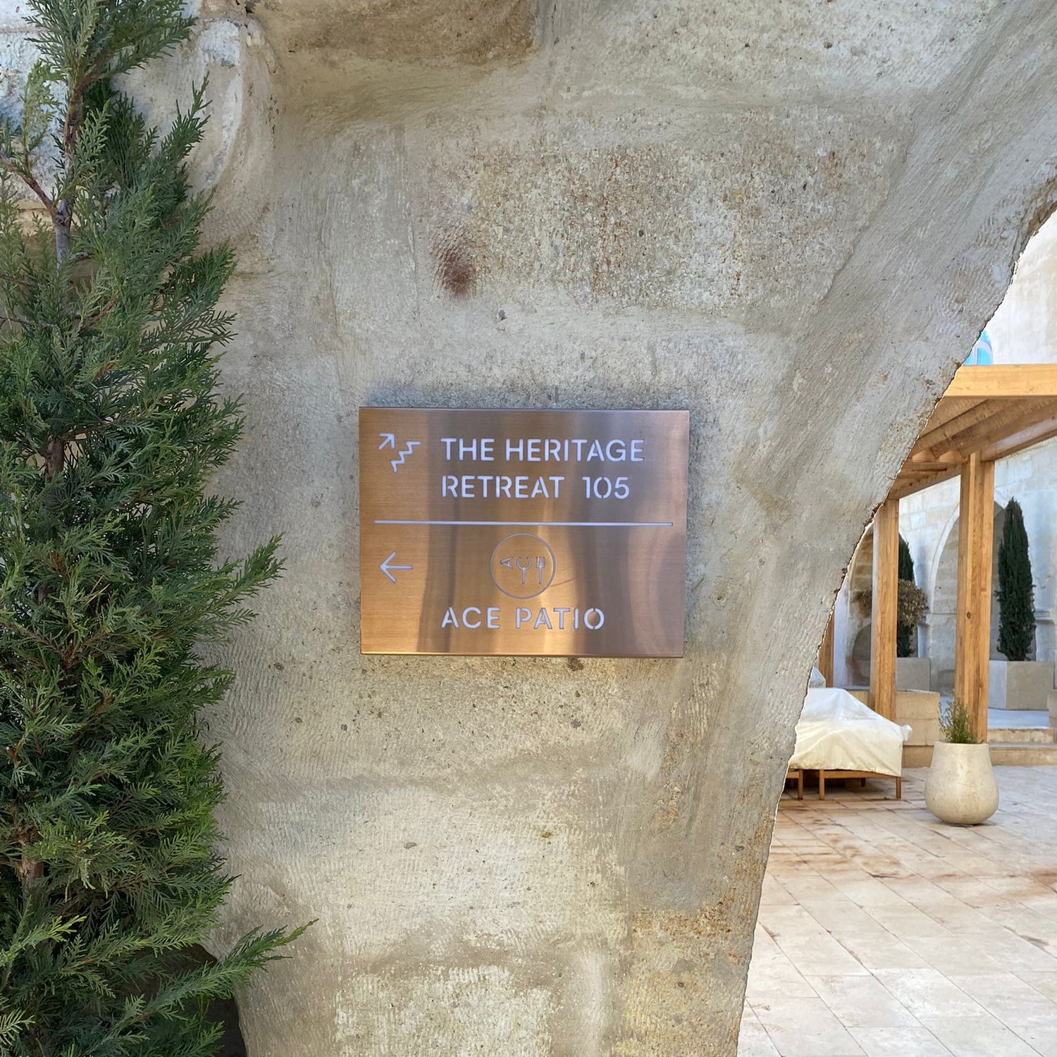 Metal sign on a stone wall with 'The Heritage Retreat 105' and 'Ace Hotel' text.
