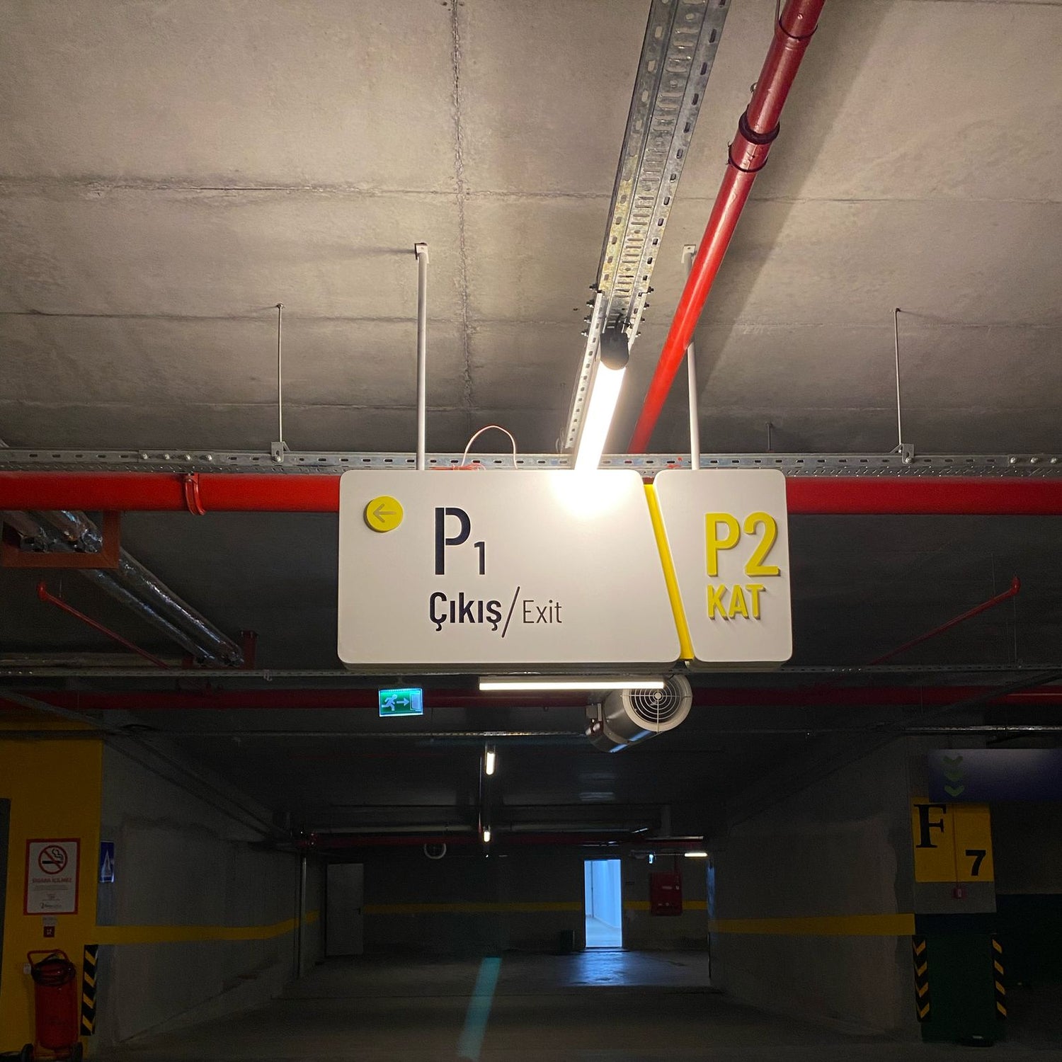 Parking garage interior with a sign indicating exit and entrance points.