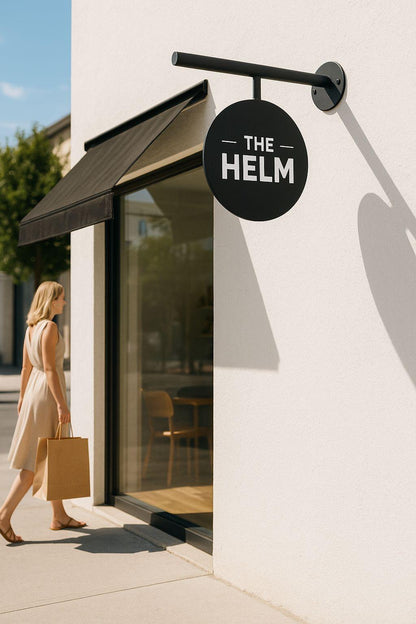 Woman walking past 'The Helm' store with a sign and awning.