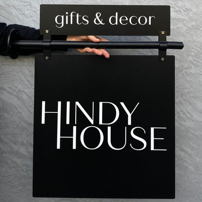 Black sign with 'Hindy House' and 'gifts & decor' text on a gray wall.