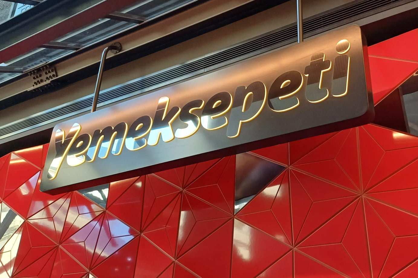 Yemeksepeti sign on a red geometric-patterned wall