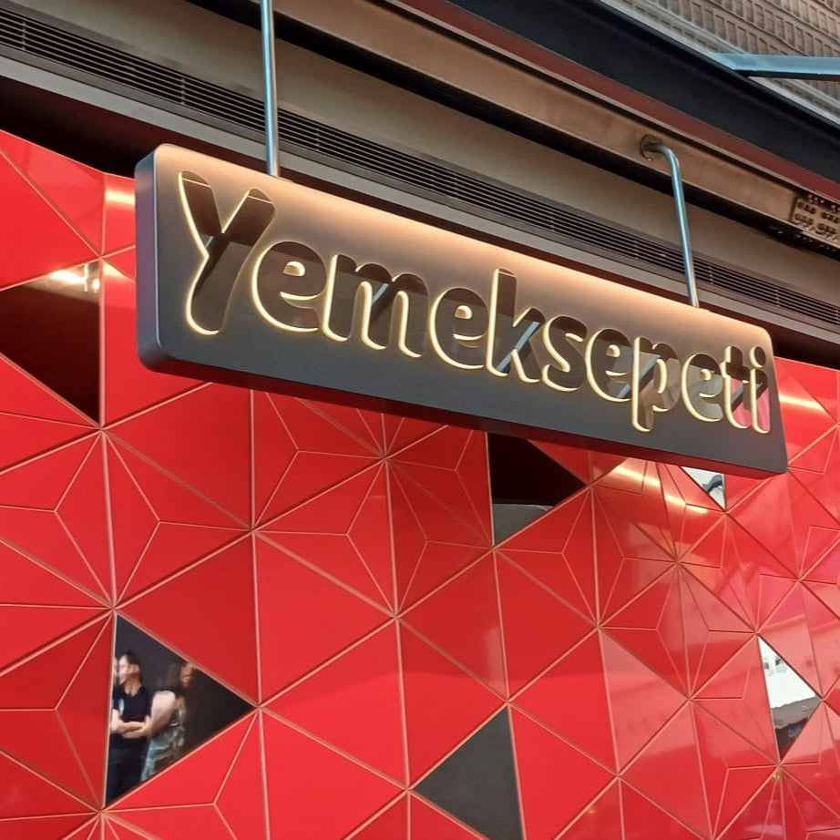 Red geometric-patterned wall with a black sign featuring 'Yelmekseptt' text.
