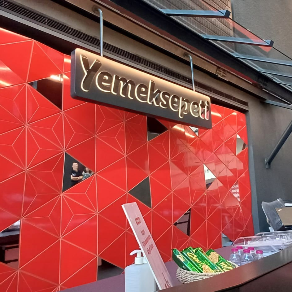Red geometric wall with 'Yemeksepeti' sign inside a building