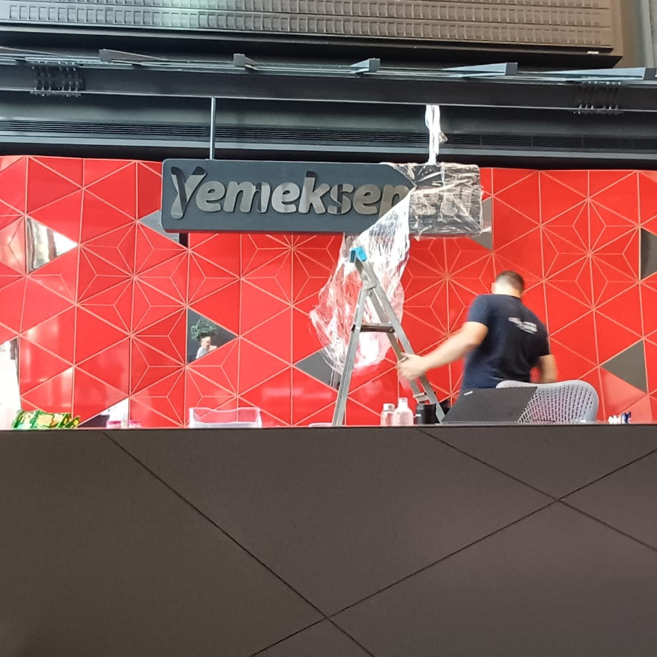 Two people shaking hands in front of a red wall with 'Yenikapöy' branding.