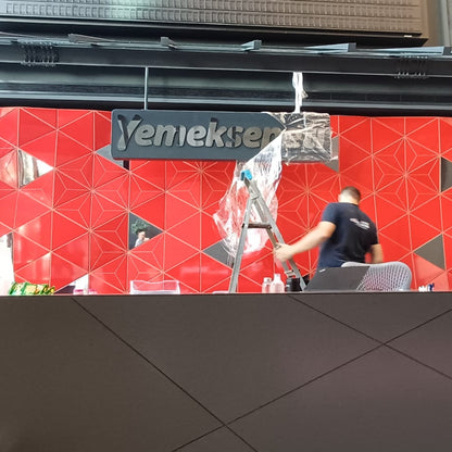 Two people shaking hands in front of a red wall with 'Yenikapöy' branding.
