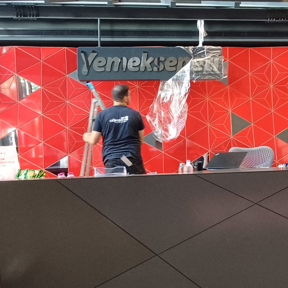 Red wall with a Venekie logo and geometric patterns, with a person standing in front.